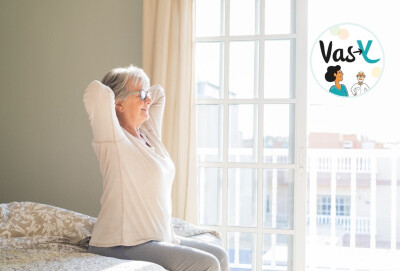 femme s'étirant en souriant et regardant par fenêtre de sa chambre après réveil