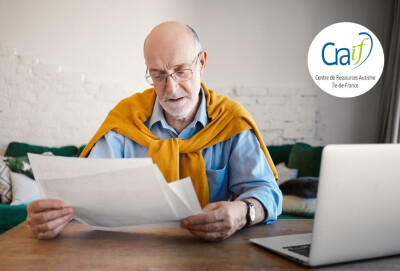homme senior regardant des documents papier ordinateur portable à côté de lui