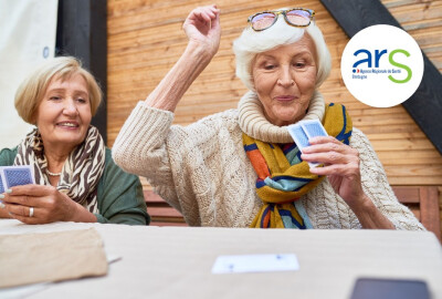 deux femmes seniors jouant aux cartes en souriant