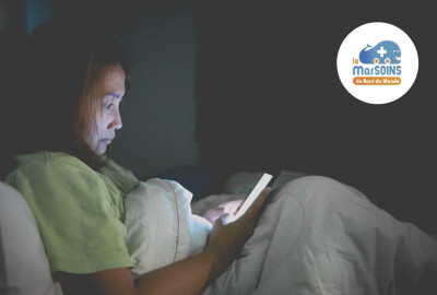 Jeune femme regardant son téléphone dans son lit la nuit