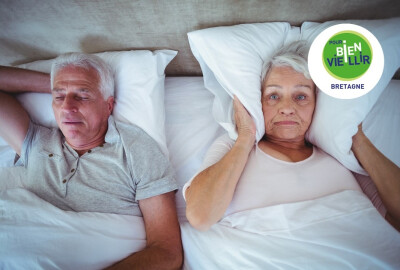 femme senior se mettant oreiller sur les oreilles pendant que son conjoint ronfle et l'empêche de dormir