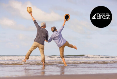 couple de seniors de dos sautant dans les vagues sur une plage