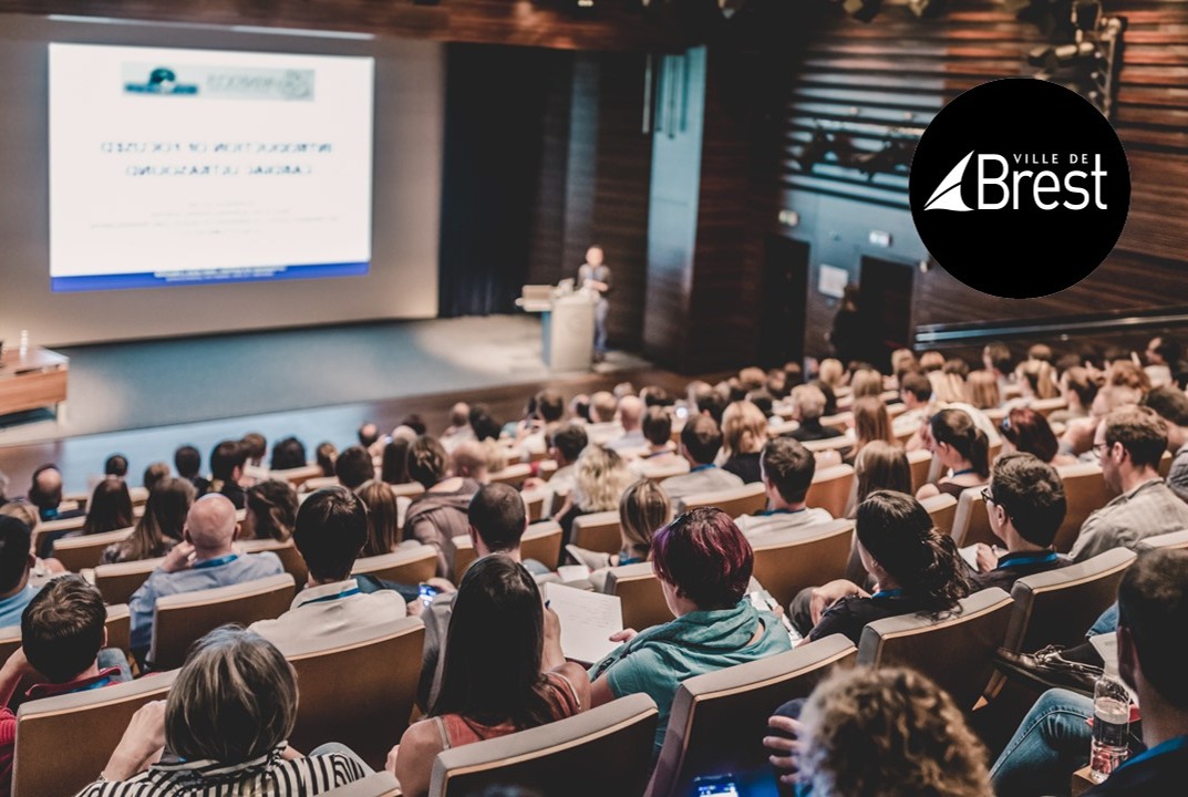 personnes de dos assistant à une conférence dans un amphi