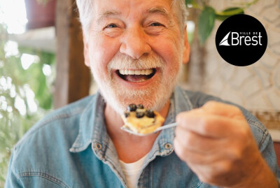 gros plan homme senior riant une cuillère remplie de gâteau à la main