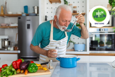 homme senior goûtant louche de soupe qu'il vient de préparer