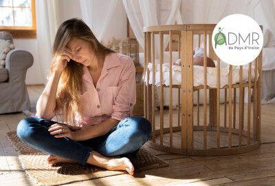 jeune maman épuisée assise devant berceau