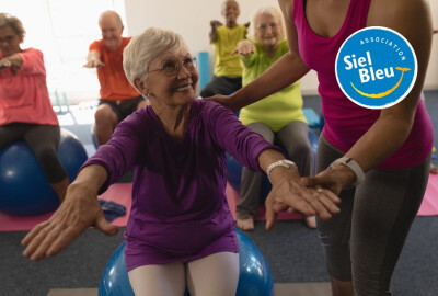 femme senior faisant des exercices sur un swissball avec l'aide d'une animatrice