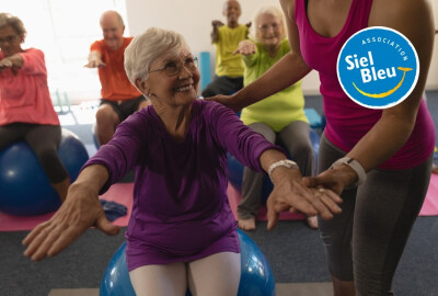 femme senior faisant des exercices sur un swissball avec l'aide d'une animatrice