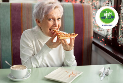 femme senior mangeant une part de pizza dans un restaurant