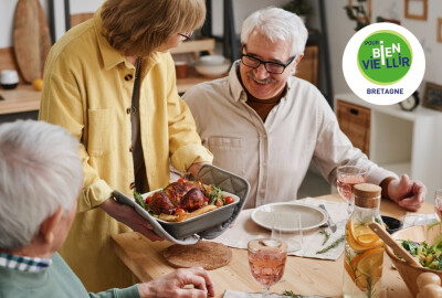 femme senior présentant un plat à un de ses convives pendant repas