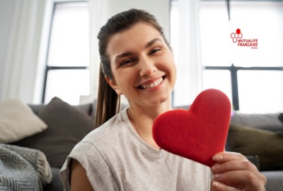 jeune femme souriante tenant un petit coussin rouge en forme de cœur