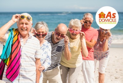 groupe de seniors souriants alignés sur la plage avec lunettes de soleil et serviettes de plage