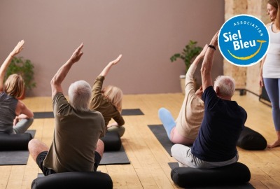 seniors faisant des exercices d'étirement des bras sur des tapis au sol pendant un cours collectif