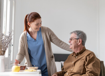 infirmière à domicile riant avec patient homme âgé