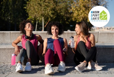 groupe de 3 jeunes femmes discutant et plaisantant assises au sol après séance de sport