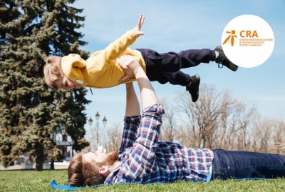 Père heureux s'amusant en plein air avec son jeune fils, en le posant sur ses jambes en l'air