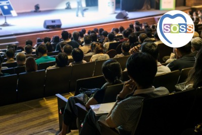 personnes de dos assistant à une conférence dans une salle de spectacle ou un amphi
