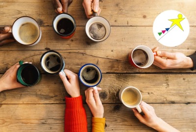 mains tenant des tasses de boissons chaudes sur une table en bois