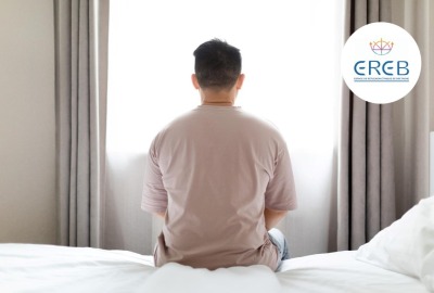 personne seule de dos assise sur un lit face à une fenêtre