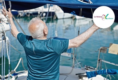 homme senior de dos levant les bras devant la mer sur un bateau