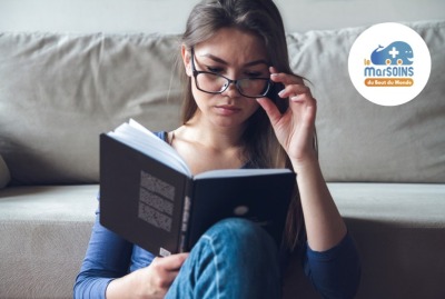 Une femme ayant des problèmes de vision voit mal à travers ses lunettes en lisant un livre