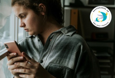 jeune fille l'air triste téléphone dans la main, regarde à l'extérieur
