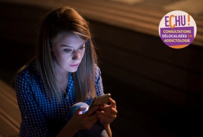 jeune femme dans l'obscurité consultant son téléphone portable