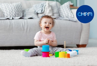 bébé riant en jouant sur un tapis avec des jouets colorés