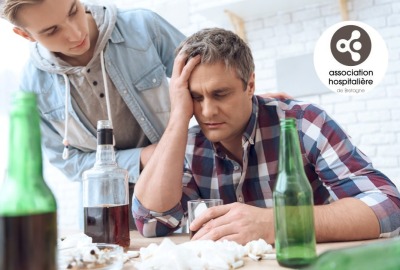 Père ivre est assis à table avec plusieurs bouteilles et cigarettes, pendant que son fils essaye de lui parler