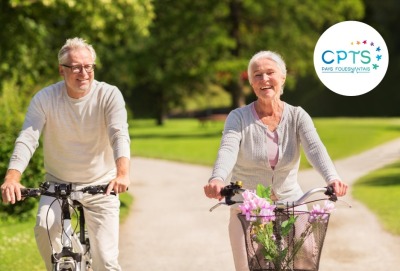 couple de seniors faisant du vélo dans un parc en souriant