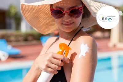 jeune femme avec lunettes de soleil et chapeau de paille se mettant de la crème solaire, au bord d'une piscine