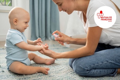 maman mettant du produit en spray sur les mains de son bébé