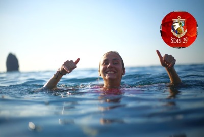 jeune fille souriant et faisant le signe que tout va bien pendant qu'elle se baigne dans la mer