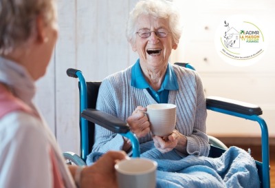 gros plan femme âgée riant aux éclats alors qu'elle prend une boisson chaude avec une autre personne visible de dos