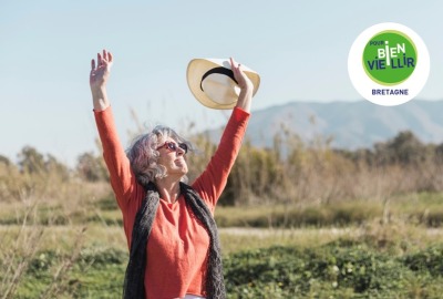 femme senior heureuse levant les bras au ciel en souriant à l'extérieur, au soleil
