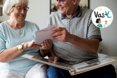 couple de seniors regardant en souriant des photos dans un vieil album