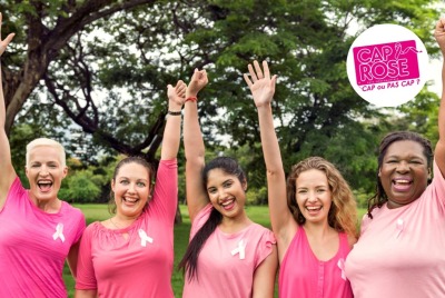 groupe de femmes en rose avec ruban rose levant les mains en riant
