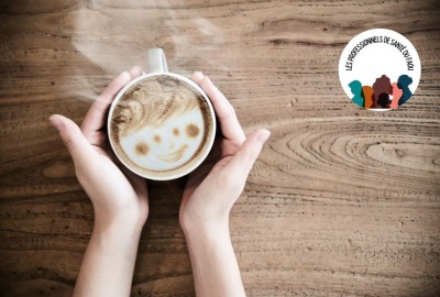 gros plan mains tenant une tasse de café avec forme de visage souriant dans la mousse
