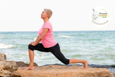 femme senior faisant une pose de yoga face à la mer