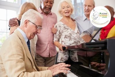 groupe de seniors chantant autour d'un homme senior jouant du piano