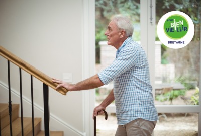 homme senior avec une canne, hésitant devant l'escalier de sa maison