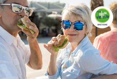 couple de seniors mangeant des hamburgers au soleil