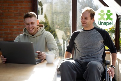 deux jeunes hommes, dont l'un en situation de handicap, consultant un ordinateur portable