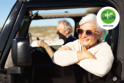 couple de senior en voiture, femme passant la tête par la fenêtre de la portière en souriant