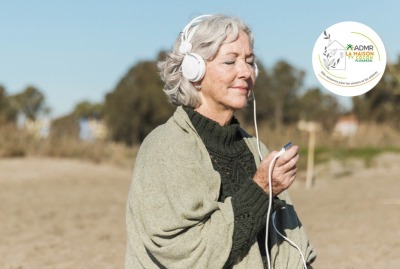 femme senior écoutant de la musique dans un casque, sur la plage