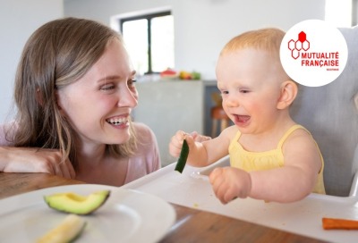 maman regardant en riant son enfant jouant pendant son repas