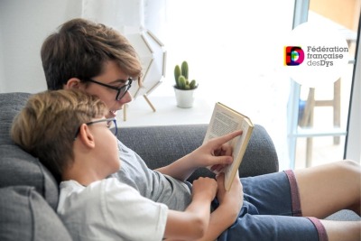 deux jeunes frères lisant un livre ensemble sur un canapé
