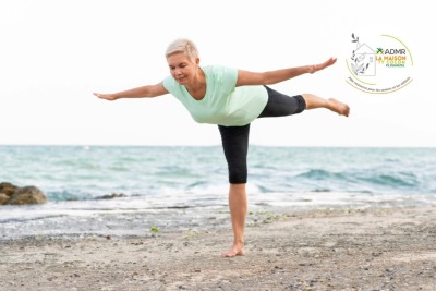 femme senior faisant une posture de yoga sur la plage