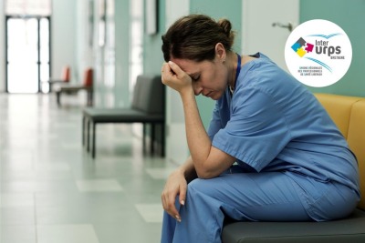 soignante épuisée se tenant la tête assise dans un hall d'hopital