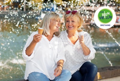 deux femmes seniors mangeant une glace sur le bord d'une fontaine